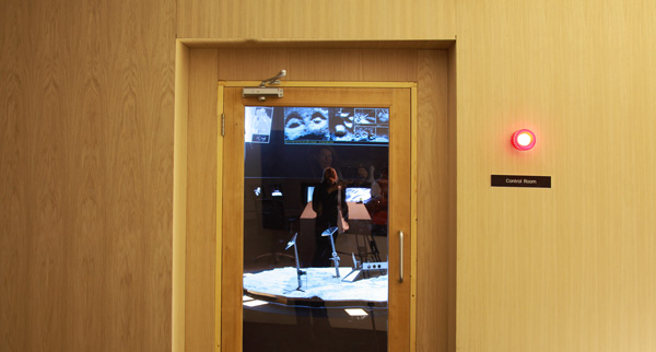 Glass door of the entrance area with view into the MGA control room